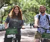 Two people smiling while riding bicycles labeled Savannah Bike Tours on a tree-lined street
