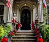 The entrance of a stately home is decorated with festive ornaments including nutcracker statues and poinsettias suggestive of holiday season adornment