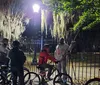 A group of cyclists with helmets and lights on their bikes is having a conversation at night