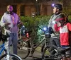 A group of cyclists with helmets and lights on their bikes is having a conversation at night