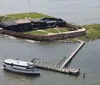 The image shows an aerial view of a coastal star-shaped fortress with a large flagpole at the forefront surrounded by water on three sides