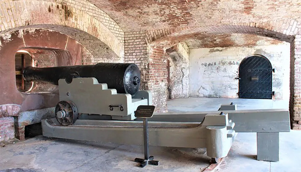 This image shows an old cannon mounted on a carriage inside a brick-walled fortification with an arched ceiling suggesting it is a historical or military museum exhibit