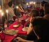 A group of surprised people sits at a dimly lit dinner table with lit candles appearing to react to an unexpected event