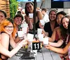 A group of people is smiling at the camera while holding up drinks at an outdoor table marked with the number 11