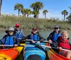 A group of smiling people are enjoying kayaking together on a sunny day in a calm waterway with grassy banks