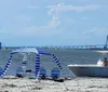 A group of people is enjoying a sunny day out on the water with some on a boat and others in an attached floating ring