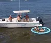 A group of people is enjoying a sunny day out on the water with some on a boat and others in an attached floating ring