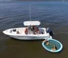 A group of people is enjoying a sunny day on a motorboat on calm waters with a bridge in the distant background