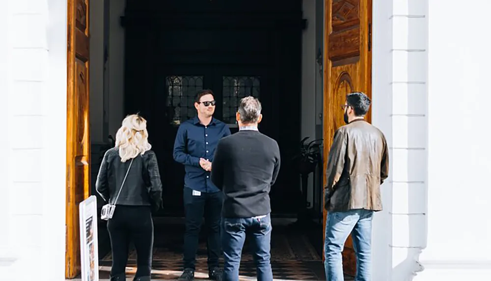 Four individuals stand at the entrance of a building seemingly engaged in a conversation