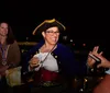 A group of people is attentively listening to an individual dressed in period costume during what appears to be a nighttime ghost tour outside a historical building