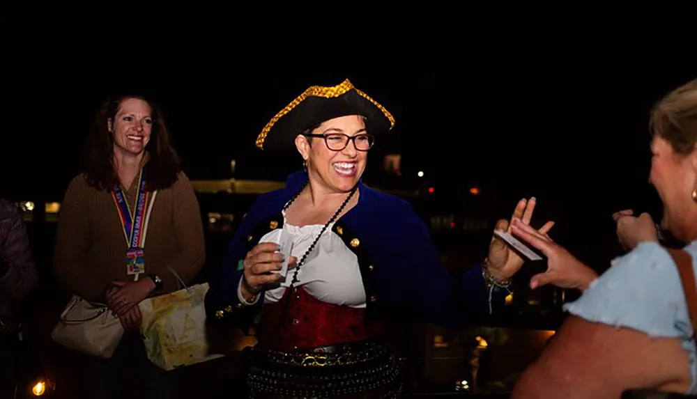 A smiling person dressed in a pirate costume enjoys an evening event with other cheerful attendees