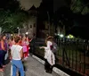 A group of people is attentively listening to an individual dressed in period costume during what appears to be a nighttime ghost tour outside a historical building