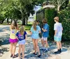 A group of children is standing at a gate entrance looking towards a house in the distance