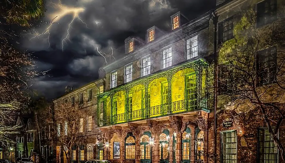 A striking old building with glowing yellow windows stands out against a dark stormy sky punctuated by dramatic lightning