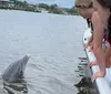 People on a boat are interacting with a dolphin that is surfacing near them