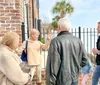 A group of people is engaged in conversation outside a brick building likely on a guided tour or a casual outing