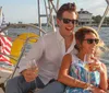 A happy couple is enjoying a sunny day on a sailboat each holding a glass of wine with the American flag in the background