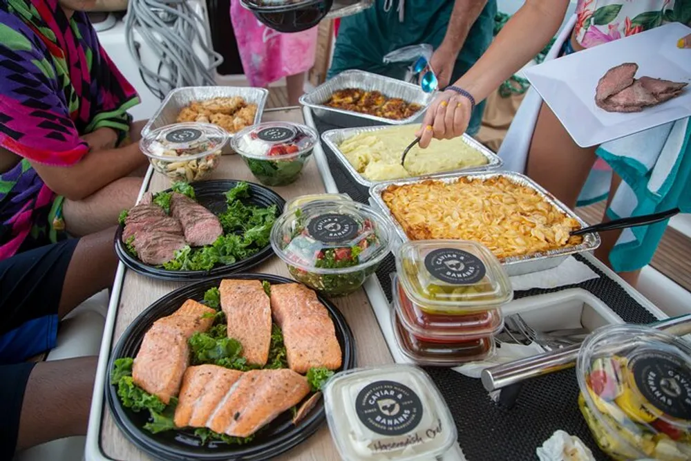 A spread of various dishes including salmon salad sliced beef and sides on a table with people serving themselves