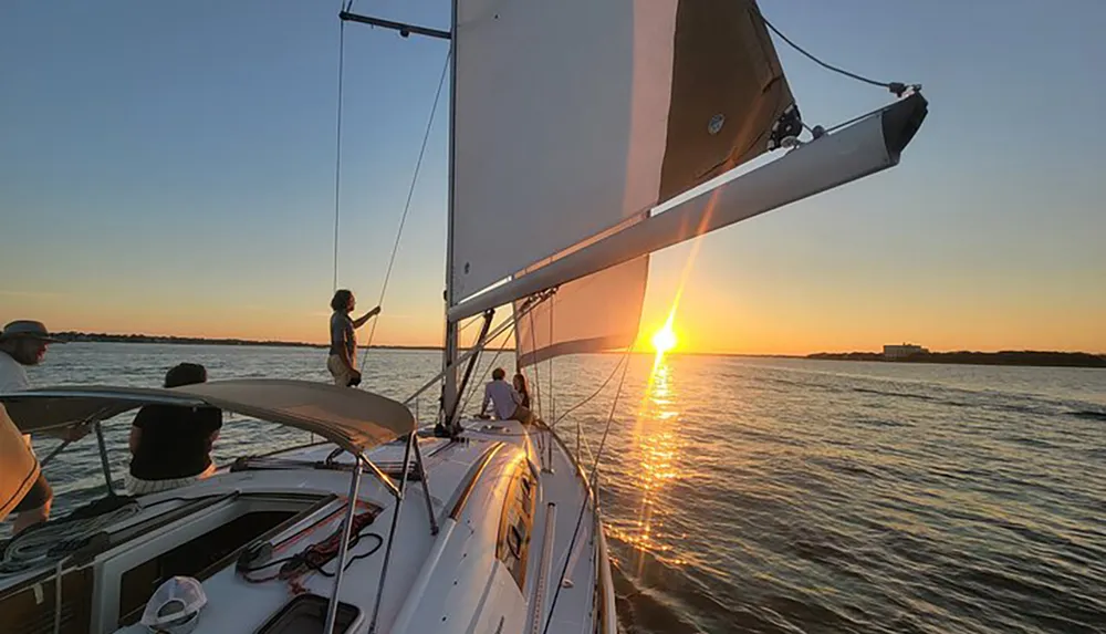 A group enjoys sailing on a yacht at sunset with the warm glow of the sun reflected on the water