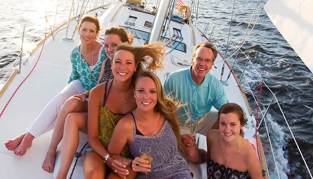 A group of happy people is posing for a photo on a sailboat during a sunny day on the water