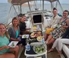 A group of smiling people are enjoying a meal together on a sailboat