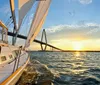 A group of people relaxes on a sailboat enjoying the sunset over the water