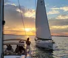 A group of people relaxes on a sailboat enjoying the sunset over the water