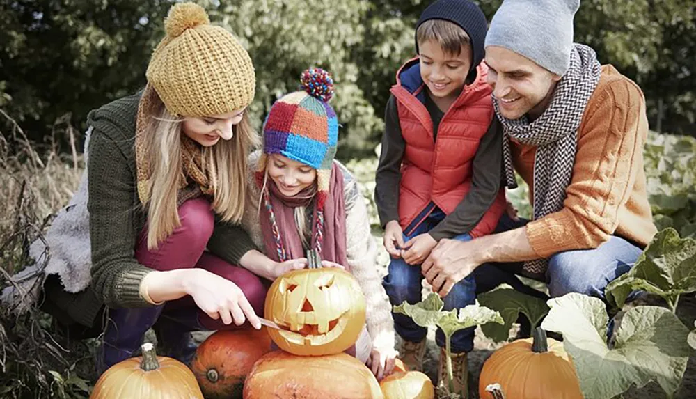 A family is happily engaged in carving a pumpkin together outdoors surrounded by autumn foliage