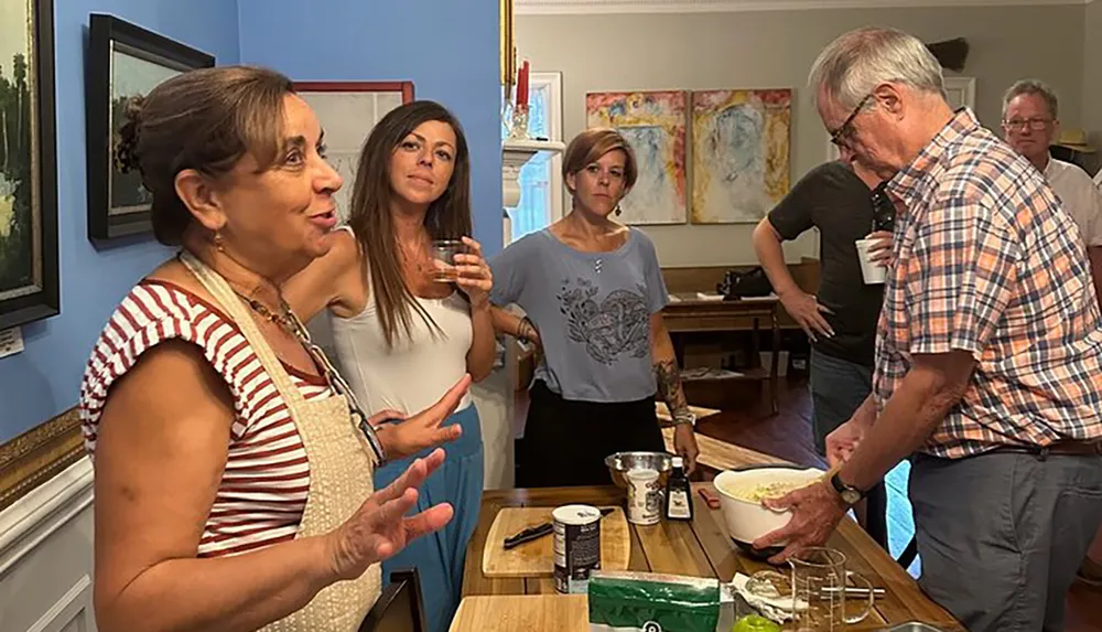 A group of people are gathered in a room possibly enjoying a social event with several individuals engaged in conversation and food preparation