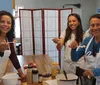 Three smiling people likely a family are wearing aprons and tasting food in a kitchen setting