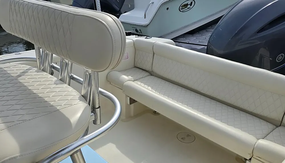 The image shows a close-up view of a boats white upholstered seating with diamond stitching set against the backdrop of a marina