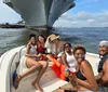 A group of friends is smiling and enjoying a sunny day on a boat with a large ship in the background