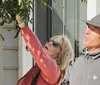 A group of people are attentively listening to a woman gesturing with her hand as if she is guiding a tour on a city street