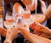 Five women are smiling for a photo at a table with drinks in a social setting