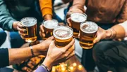 A group of people is toasting with glasses of beer in a social gathering.