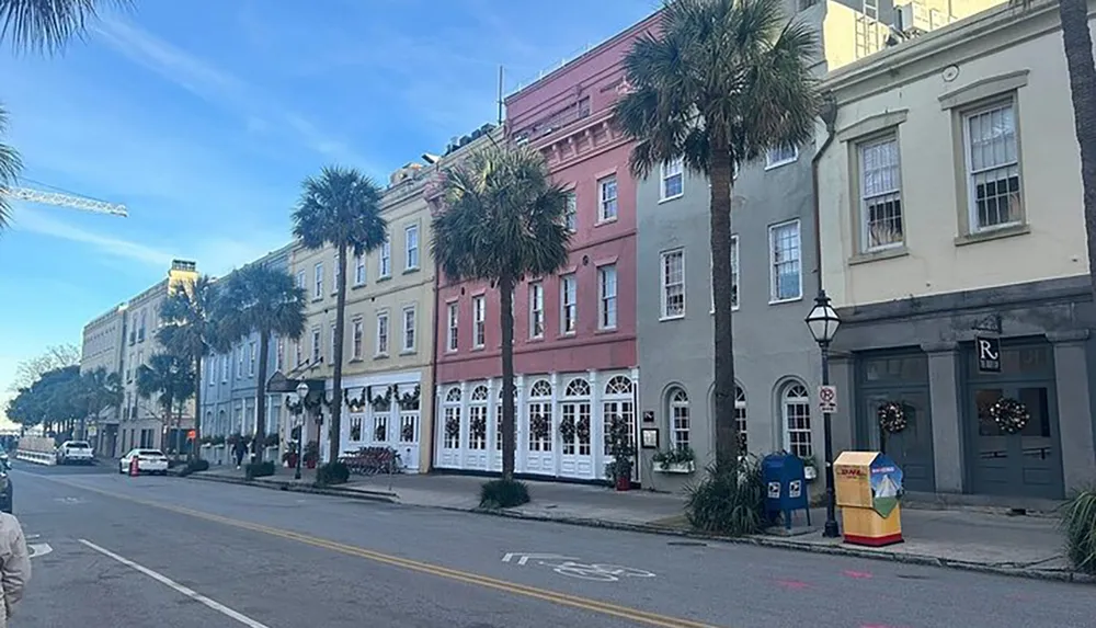 This image shows a street lined with colorful historic buildings and palm trees under a clear blue sky capturing the charming architecture of a downtown area