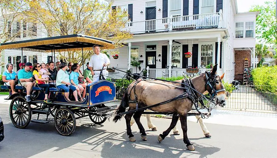 A horse-drawn carriage is carrying passengers on a sunny day past residential buildings, guided by a coachman.