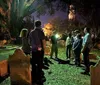 A group of people stands attentively in a cemetery at night possibly on a guided tour or historical walk illuminated by the glow of a flashlight and ambient light
