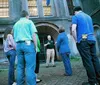 A group of people is listening attentively to a guide who is speaking in front of a historic building with barred windows