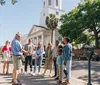 A group of people is engaged in a guided tour on a sunny day in a city street with historical architecture in the background