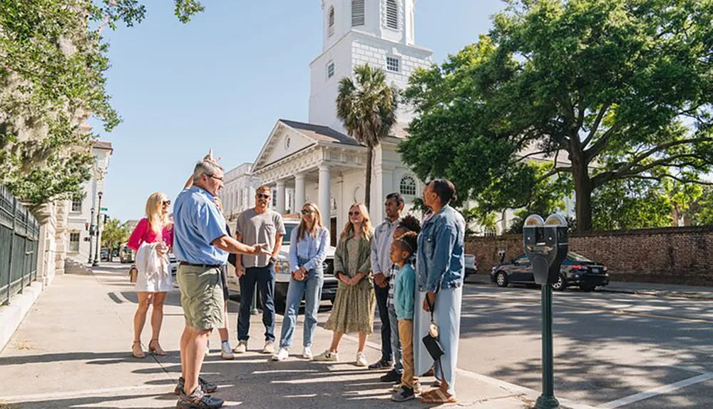 A group of people is engaged in a guided tour on a sunny day in a city street with historical architecture in the background