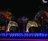 The image depicts a vibrant blue Christmas tree with glowing decorations reflecting on water set against a backdrop of illuminated buildings at night