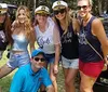 A group of five smiling women pose in front of a sign for Deep Water Vineyard indicating a winery restrooms and gift shop on a sunny day