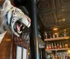 A mounted tiger head with an open mouth protrudes from a wall above the bar in a classically styled pub