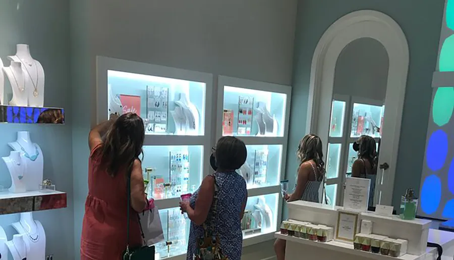 Several people are browsing items displayed in backlit cases at a well-lit, modern retail store.