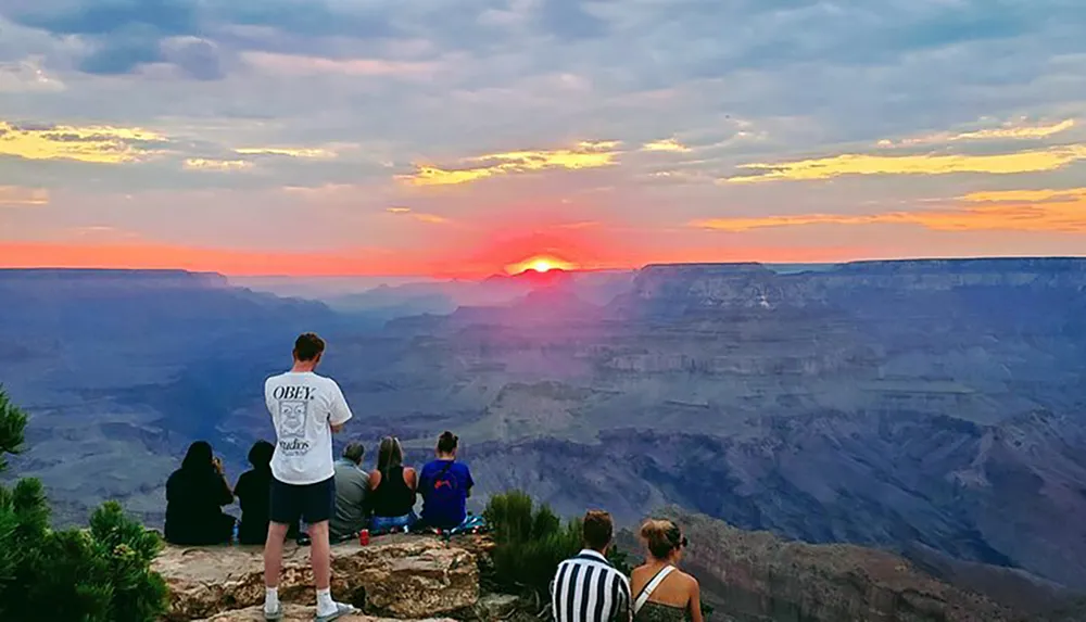 A group of people are enjoying a beautiful sunset at the Grand Canyon