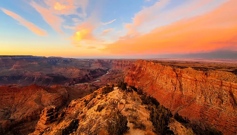 The image captures a breathtaking sunset over the Grand Canyon highlighting the vast and colorful landscape of this natural wonder