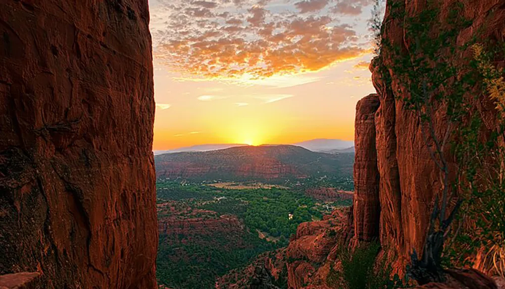 The image captures a breathtaking sunset view between two towering red rock formations overlooking a vast valley