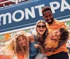 A joyful family is laughing and posing in front of the BELMONT PARK sign at an amusement park