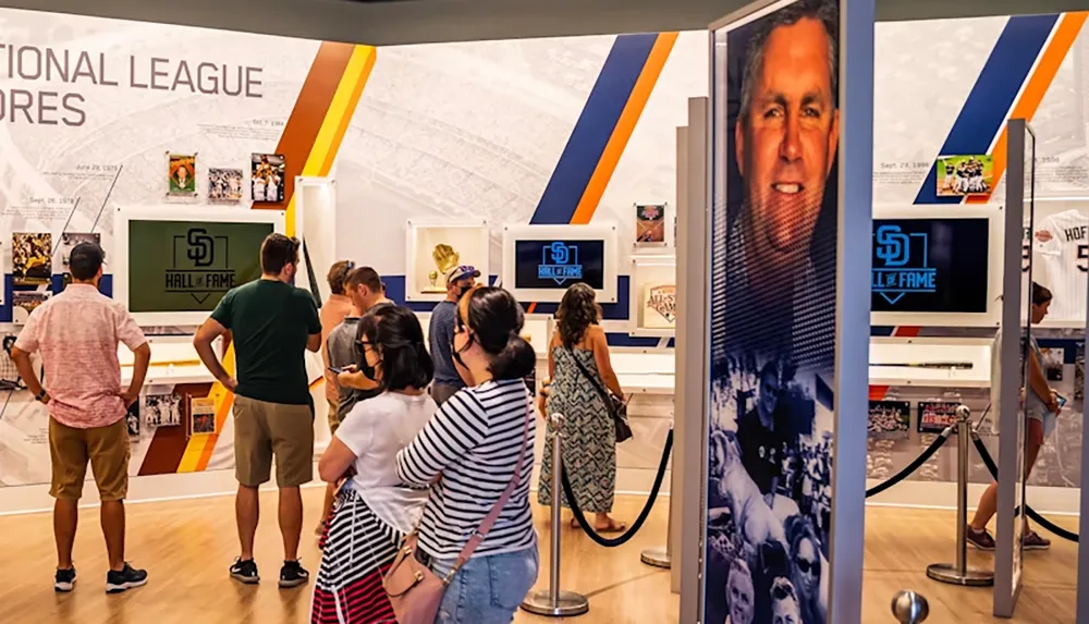 People are observing exhibits in a sports hall of fame showcasing memorabilia and historical information